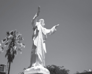 A statue of Jesus Christ, "Touchdown Jesus", sits bathed in sunlight outside Marquette Hall.
